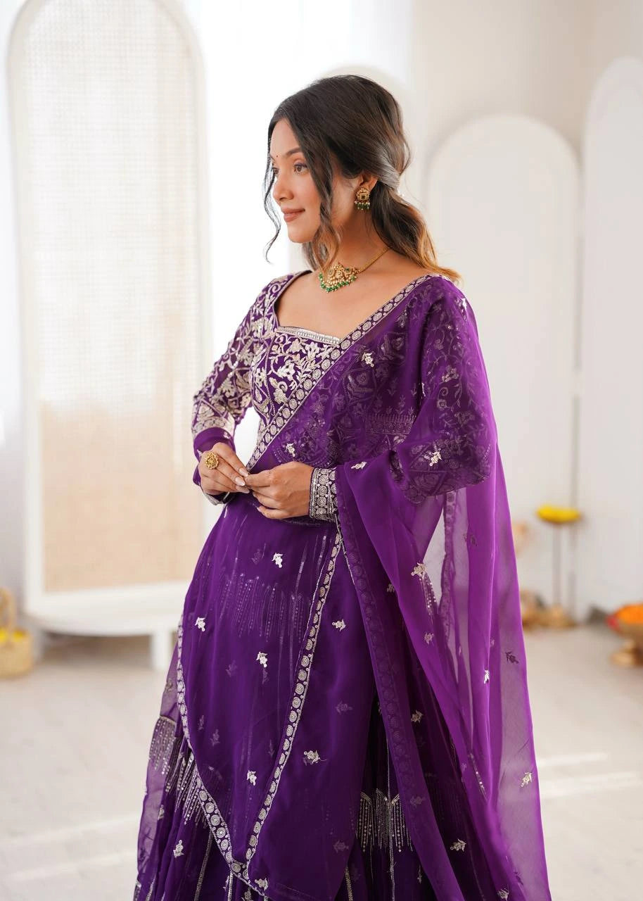 Woman wearing a purple traditional outfit with intricate designs indoors.